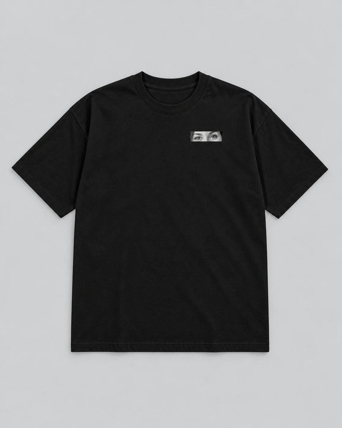 T-shirt noir Eyes, posé à plat sur fond gris