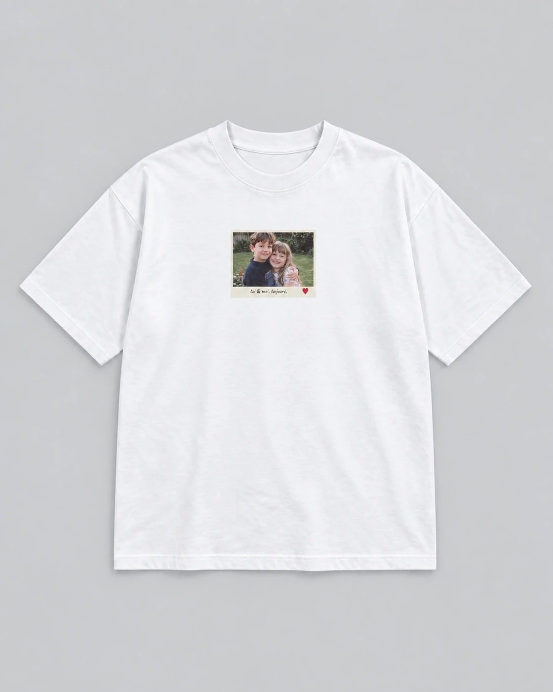T-shirt blanc Petit souvenir, posé à plat sur fond gris