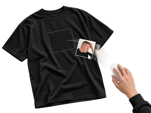 Une main utilise une souris pour faire glisser une photo vers la zone d’impression d’un t-shirt noir